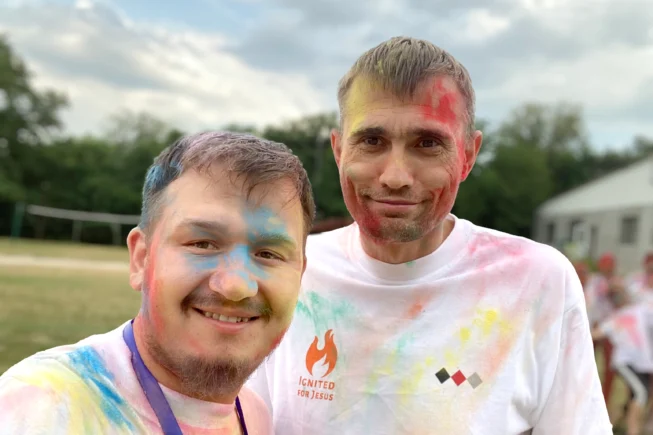 Two young men with coloured chalk splatted on their faces and tshirts