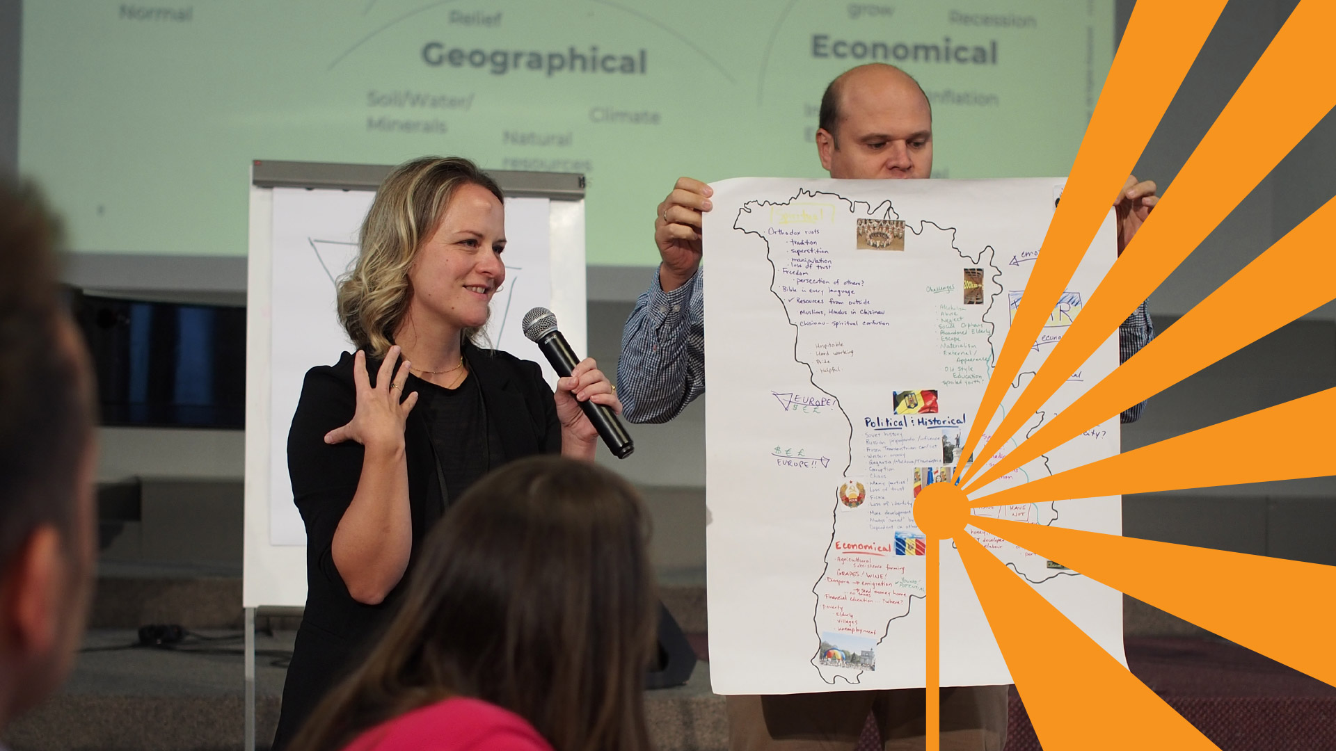 Woman presenting with microphone and man holding a hand-drawn map.